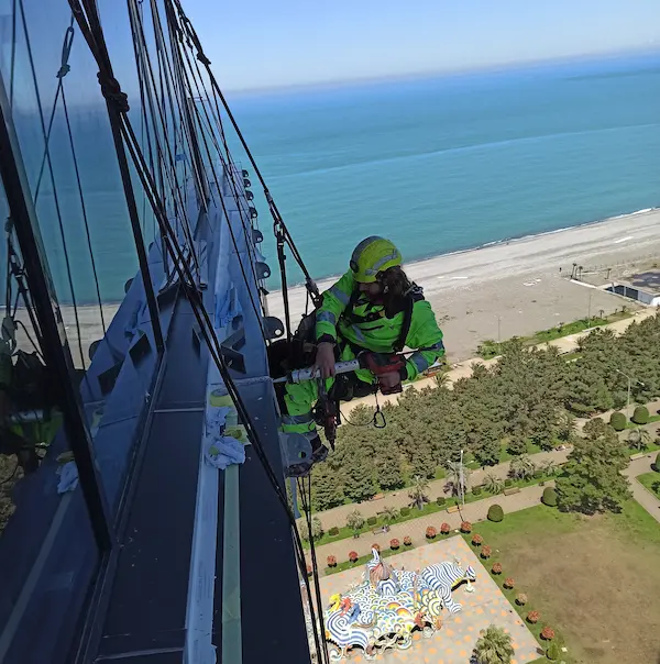 Industrial climber installing an advertising panel on a building façade